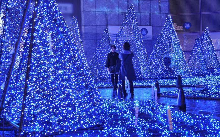 Люди фотографируются на фоне рождественских огней в Токио