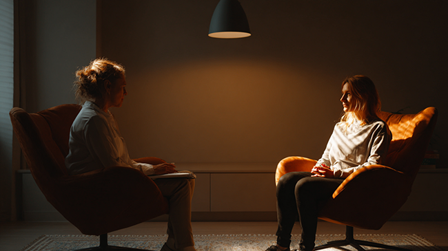 Две женщины сидят в креслах напротив друг друга в комнате в процессе психологической консультации